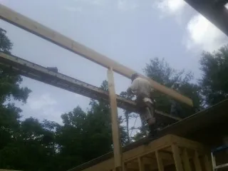 Carpenter setting a ridge beam over a new addition frame — Ice Dam Removal by Roofing Brothers in Trussville