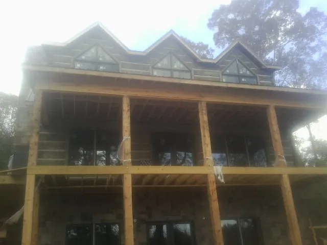 Dormers and porch framing on a large log home under construction — Roof Coating work by our crew in Trussville