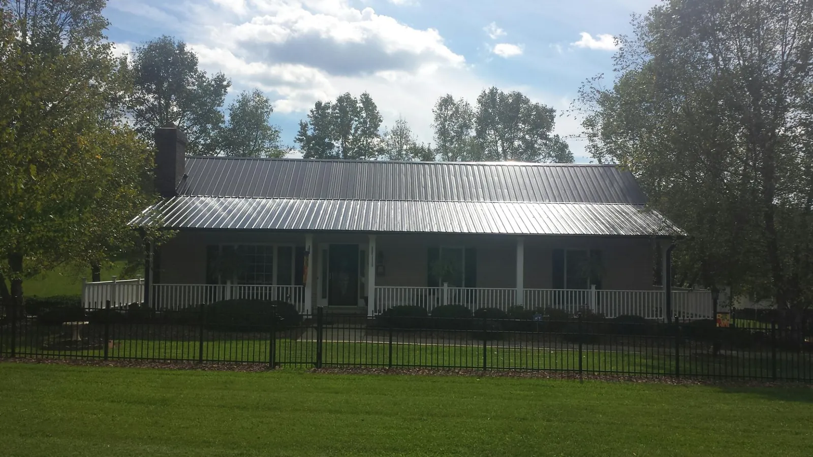 Gray metal roof on a brick ranch with a full width front porch — Gutter Guard Installation work by our crew in Trussville