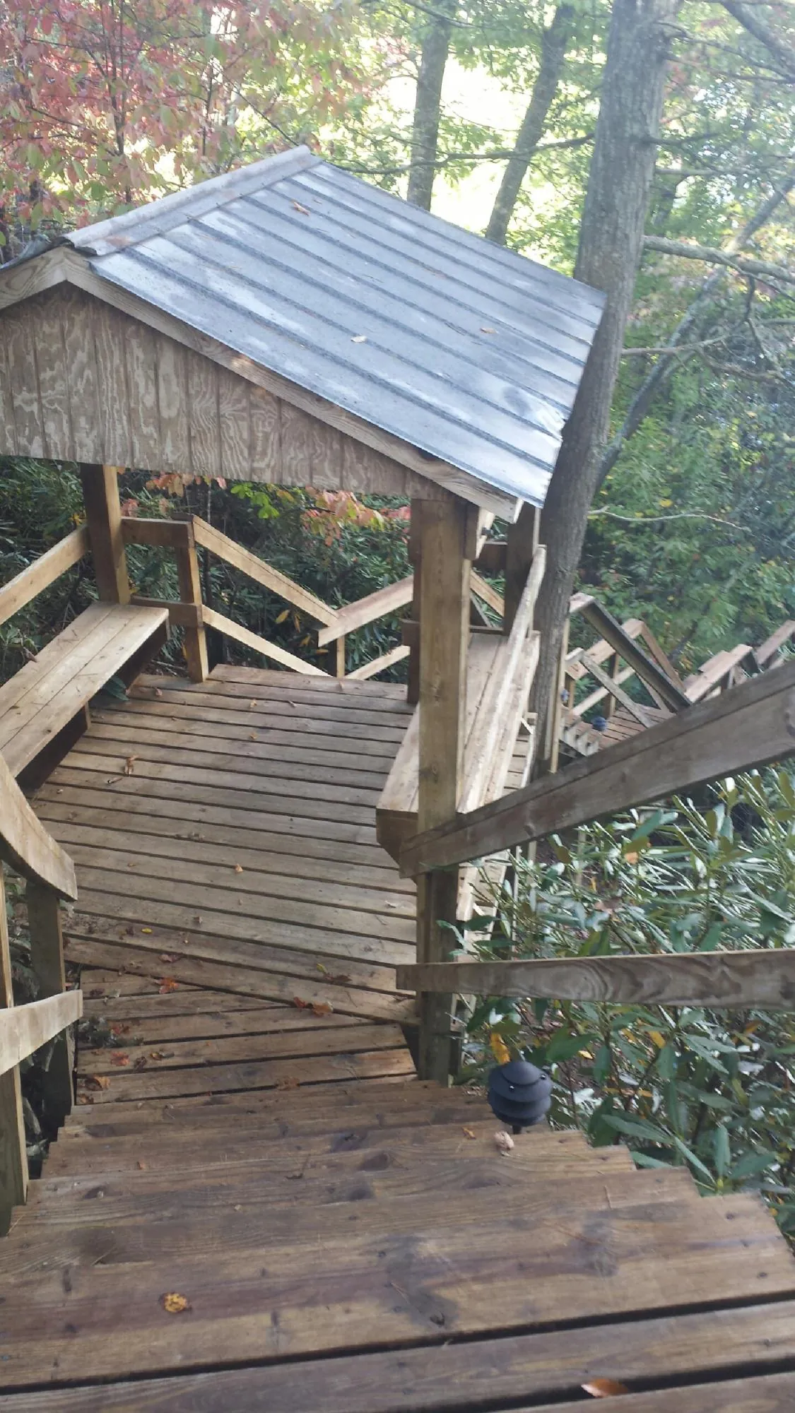 Metal roofed shelter over wooden steps on a wooded walkway — Skylight Repair & Installation work by our crew in Trussville