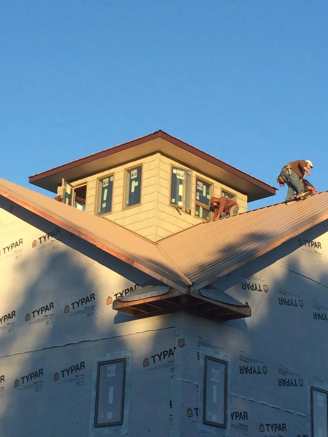 Roofers working around a rooftop cupola on a new metal roof at sunset — Roof Waterproofing in Trussville by Roofing Brothers